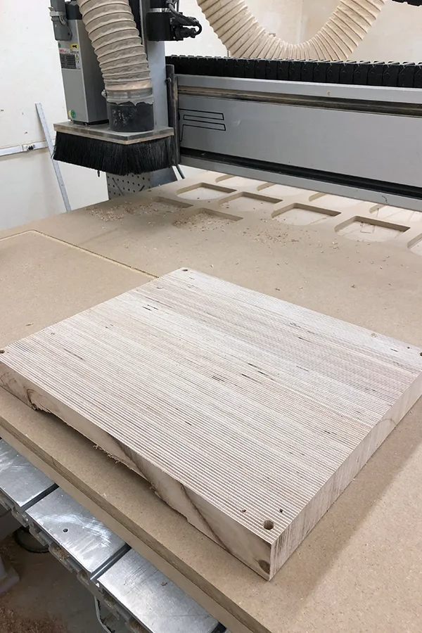 A plywood blank clamped on a CNC bed, the first passes cut