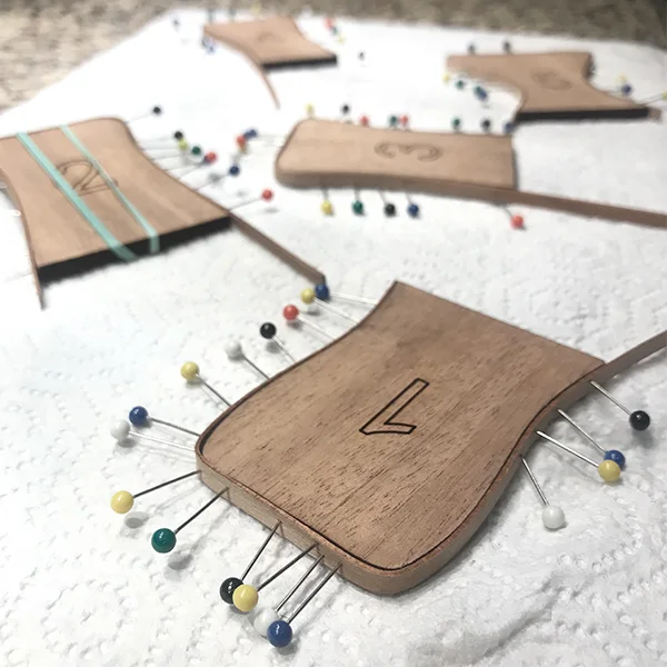 A thin plywood template pinned to a cloth with coloured pins
