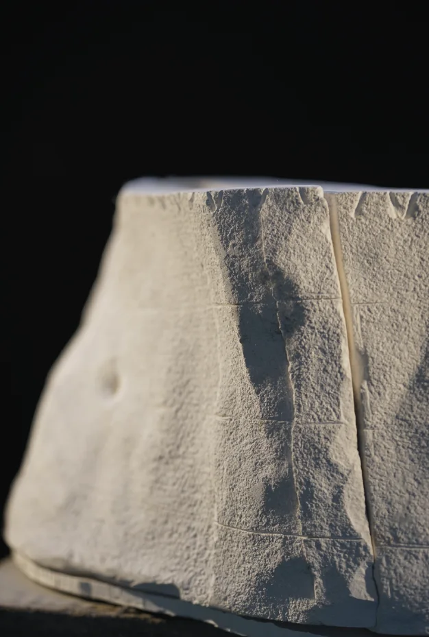 A cast tower fragment in pale stone-like material, lit against black