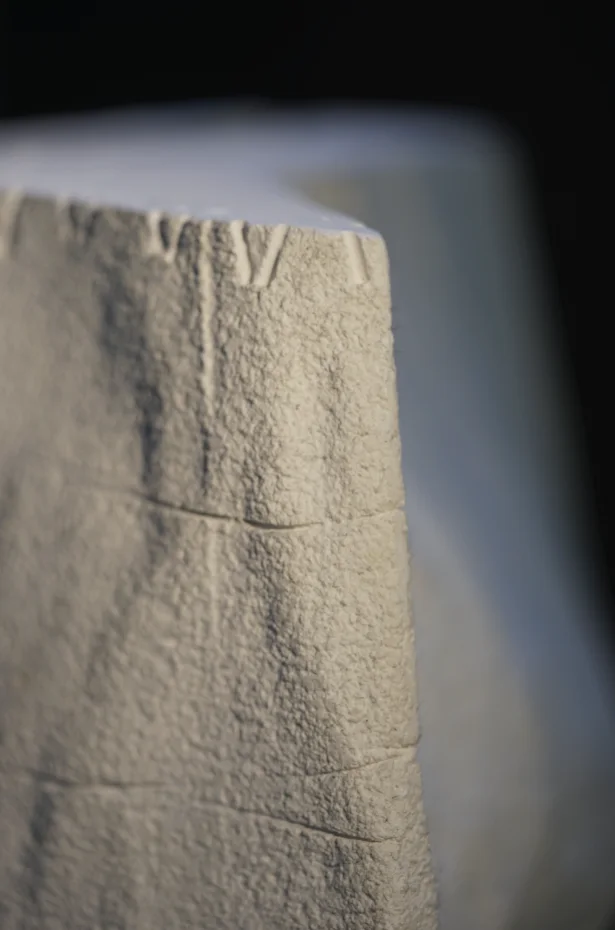 The edge of a cast block, its surface rough and layered