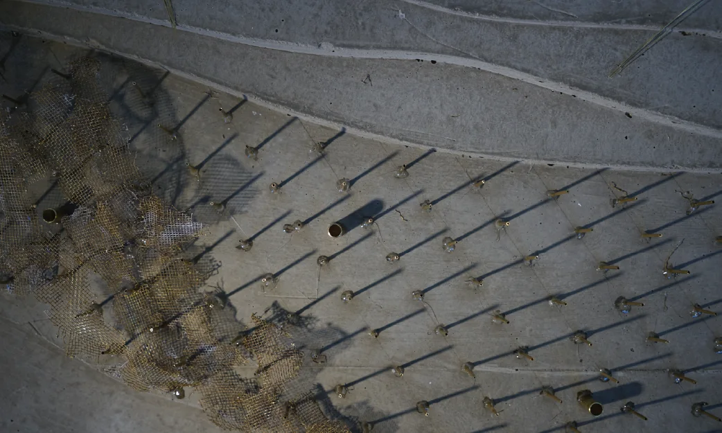 A pale relief with a grid of pins and threads stretched across it
