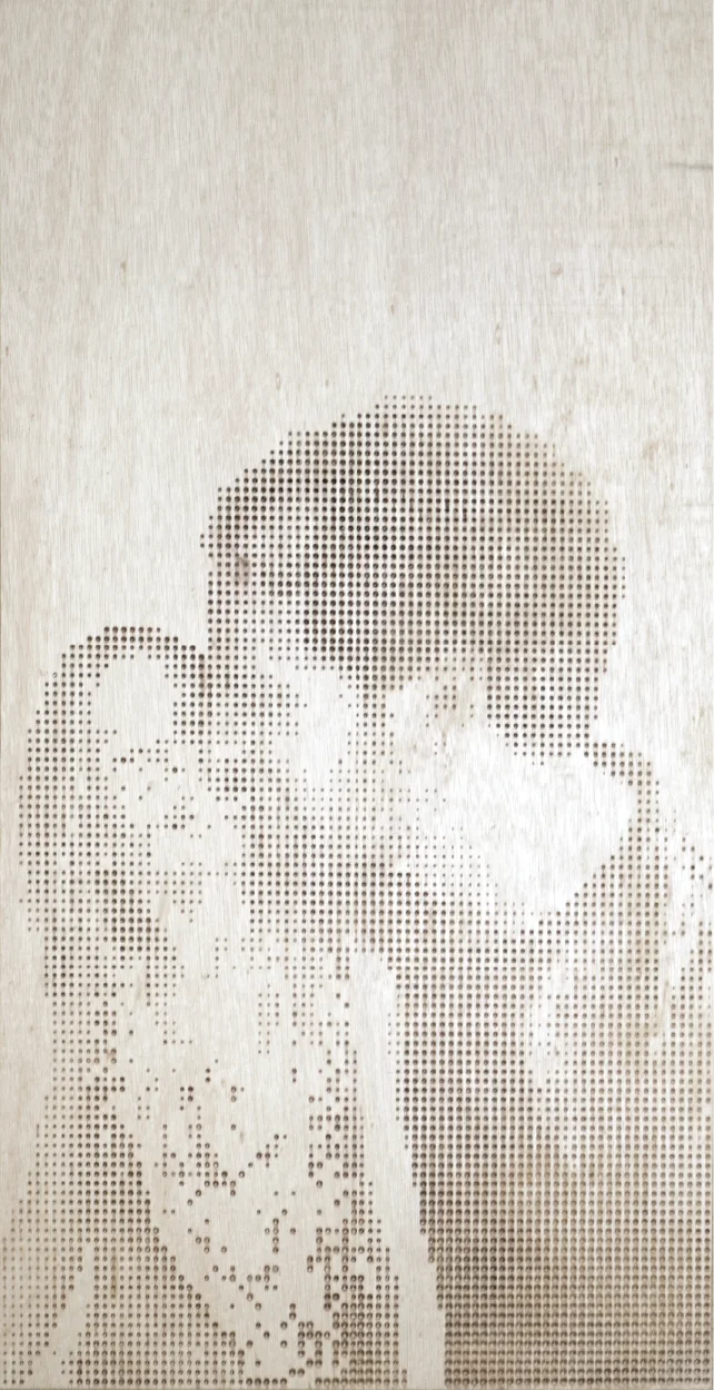 A tall plywood panel with a couple's portrait drilled into it, the woman in profile