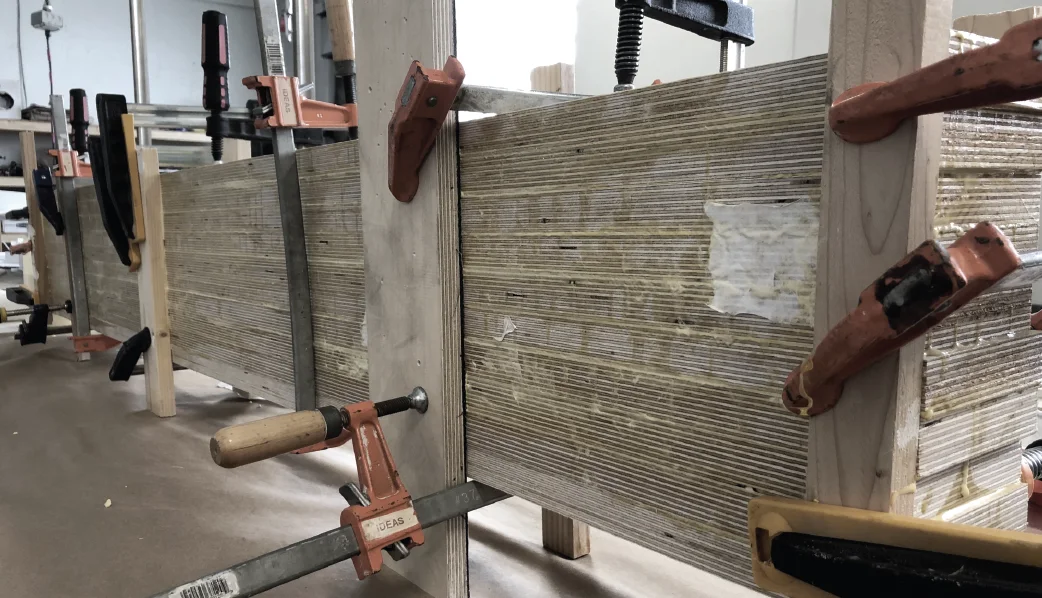 A stack of plywood sheets glued and clamped into a thick block