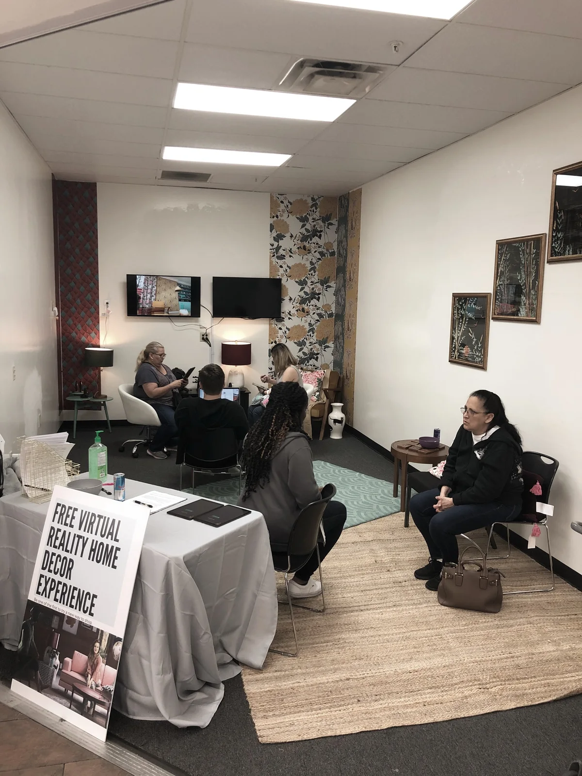 The test room: a small office with patterned wallpaper, a monitor mirroring the headset view, and a seated participant